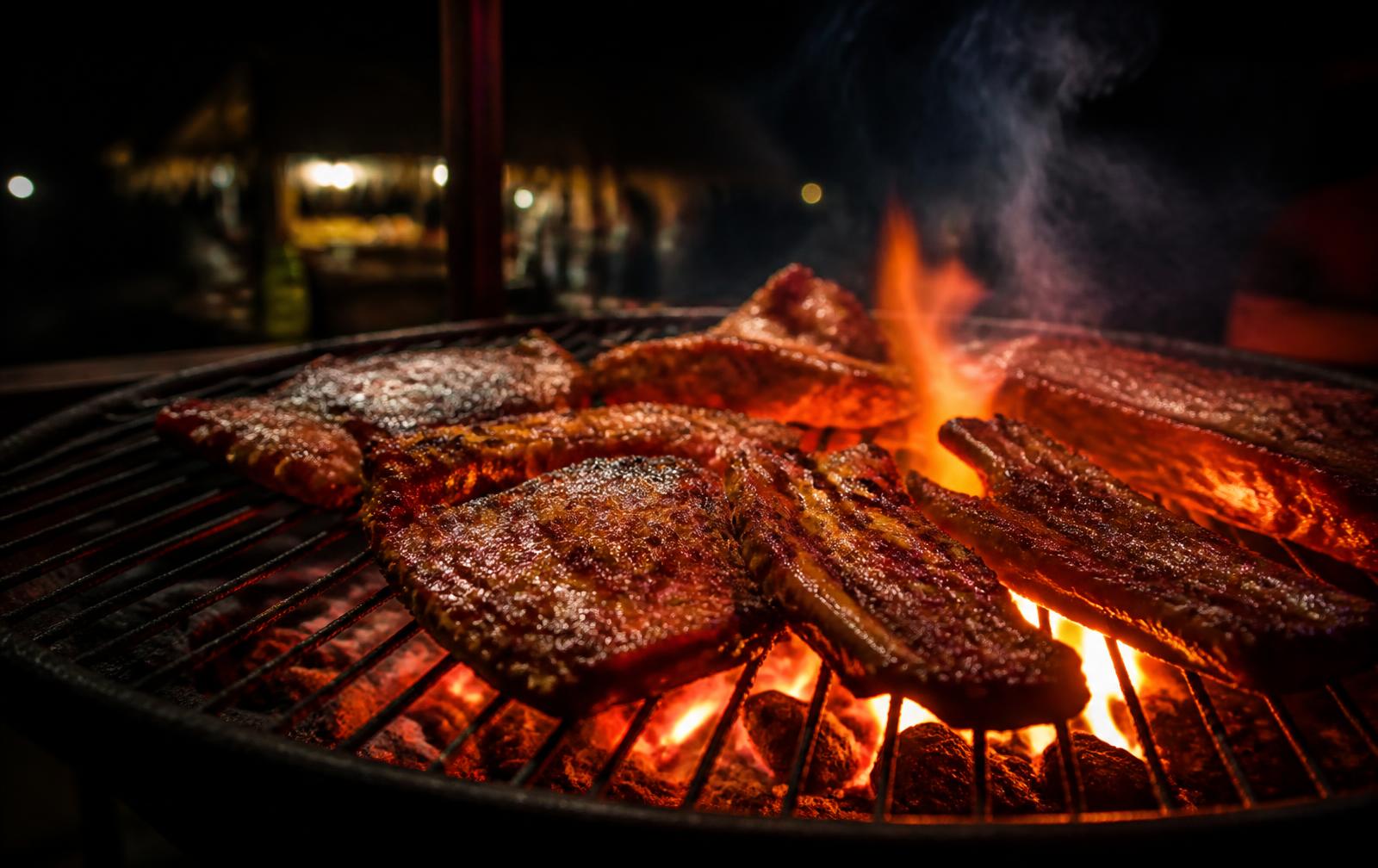 Meat grilling over open coals at Second House Grillz